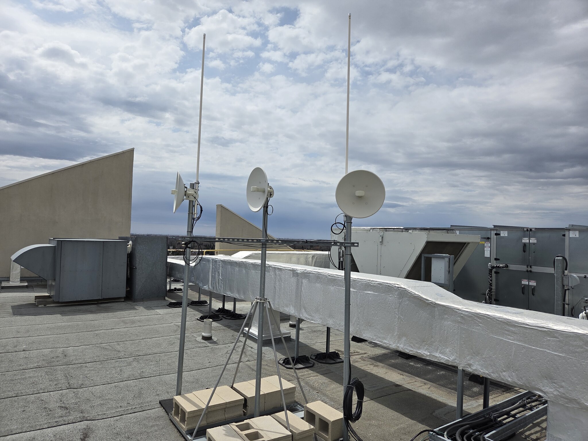 Three microwave dish antennas and two vertical antennas on a rooftop